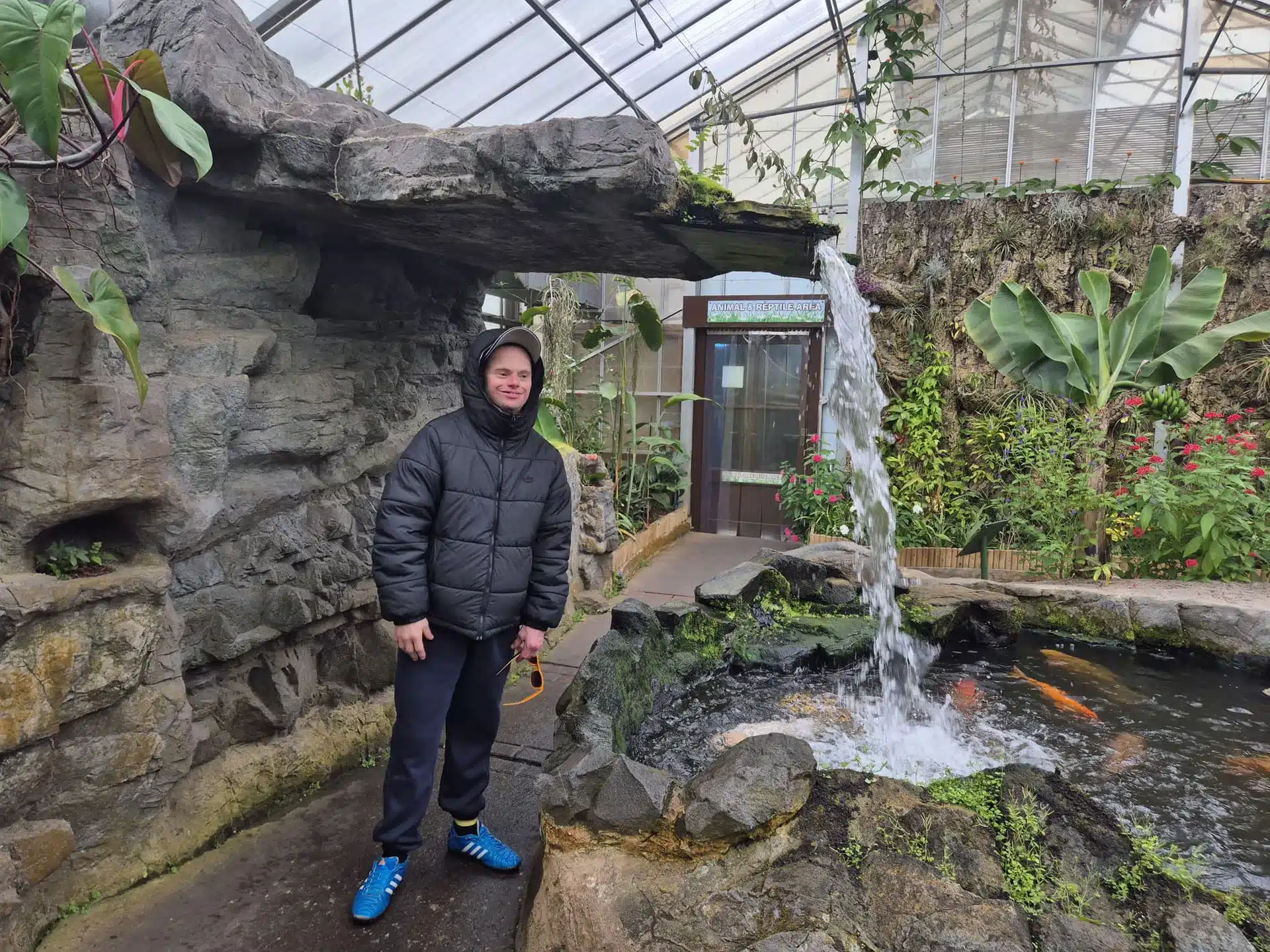 Person stood near waterfall in a greenhouse