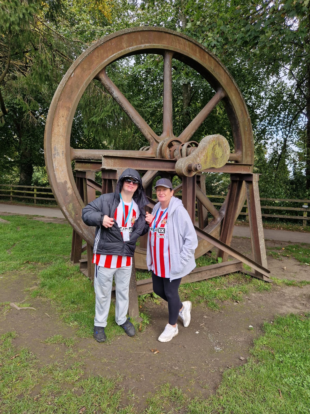 Two people wearing Sunderland football tops in front of a wheel
